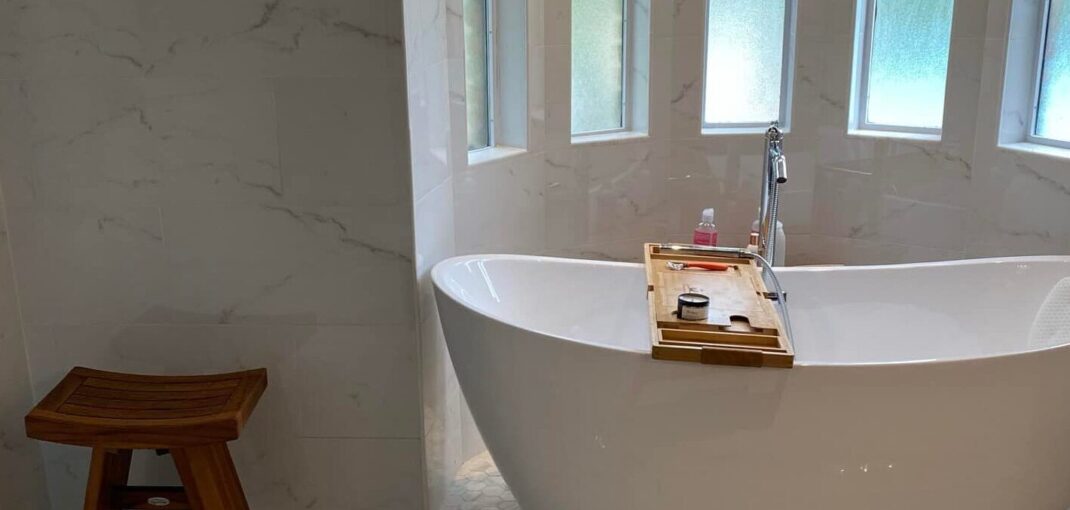 Bright white large primary bathroom with freestanding tub