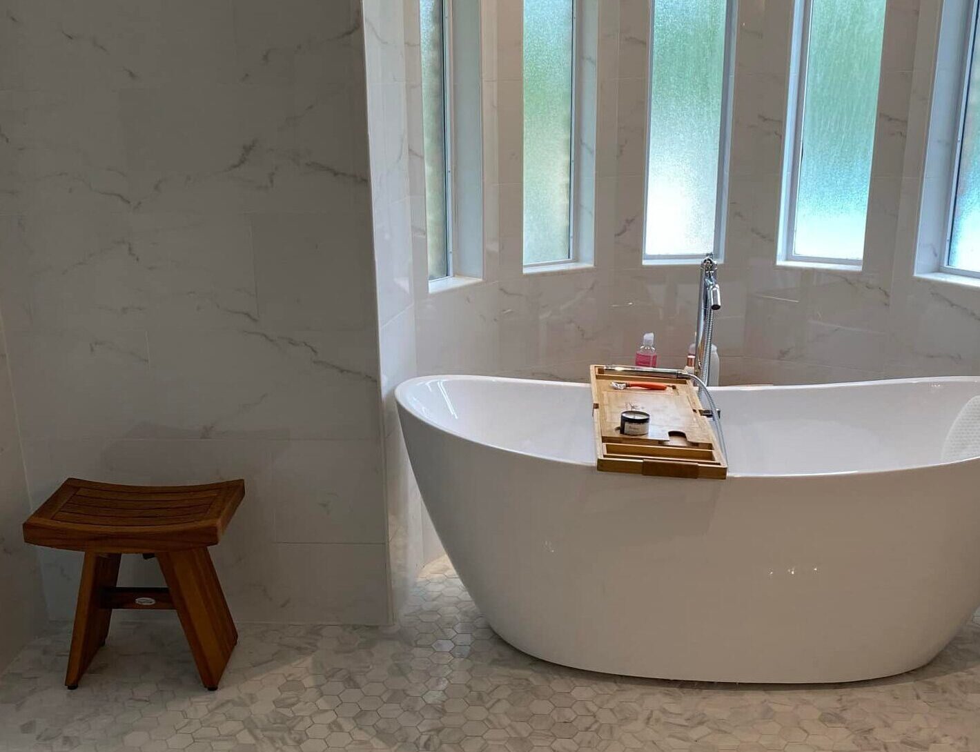 Bright white large primary bathroom with freestanding tub